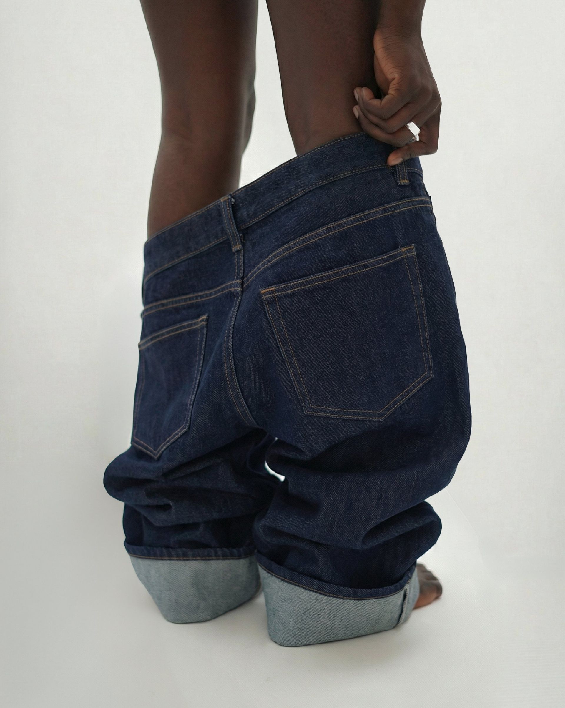 Close-up of dark blue denim jeans pulled down showing back pockets and rolled cuffs