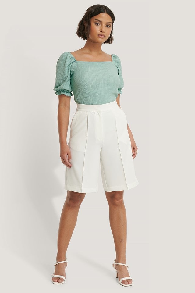 Style this trendy top, with a pair of gold-colored hoops, suit shorts, and a pair of strappy sandals. For a cute summer look.